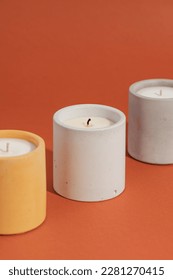 Aromatic premium soy candles in gray concrete jar on orange background. Poster banner for candle shop, beauty, spa