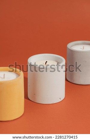 Aromatic premium soy candles in gray concrete jar on orange background. Poster banner for candle shop, beauty, spa
