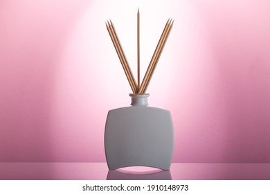 Aromatic reed air freshener on the glass table in the pink bathroom.