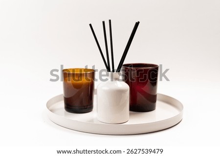 Aromatic reed diffusers and candles arranged on a decorative tray, isolated on a white background, composition evoking relaxation, aromatherapy, and home spa atmosphere