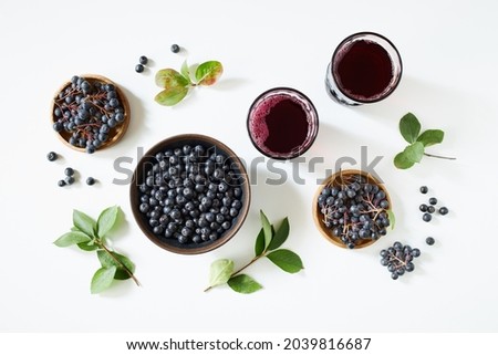 Aronia berries and juice on white background.