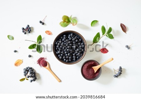 Aronia berries and powder on white background.