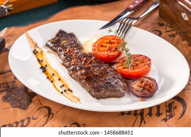 arrachera mexican spiced skirt steak with grilled tomatoes and onion on old map background side view