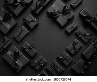 Arranged Gifts boxes wrapped in black paper with black ribbon on black background. Christmas concept - Powered by Shutterstock