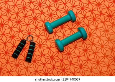 Arranged On An Orange Exercise Mat, Weights And Equipment For Home Training. Free Space For Text On A Sport Theme.