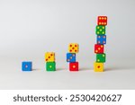 Arrangement of brightly colored and different sized dice in progress and growth representation concept, against white background