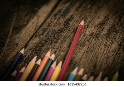 Arrangement Of Colored Pencils On A Dark Brown Wooden Table. Cinematic Concept To Keep On Being Creative And A Way To Motivate Children To Continue Their Education.