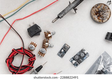 arrangement of different electrical tools on grey background. multimeter, converter, adapters, heat shrink etc.