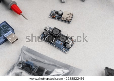 arrangement of different electrical tools on grey background. multimeter, converter, adapters, heat shrink etc.
