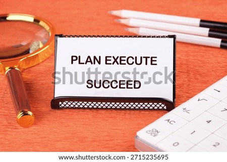 Arrangement features Plan Execute Succeed note card, pencils, calculator, and magnifying glass. It conveys strategy, careful planning, and the pursuit of accomplishment.