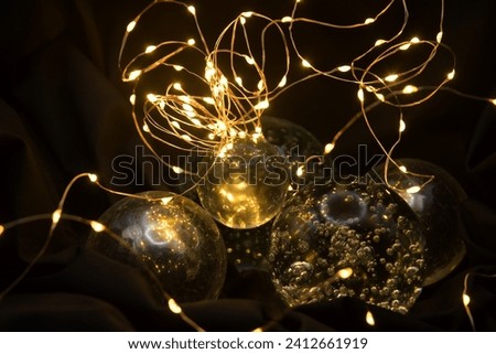 Arrangement of fivve glass spheres on a black background with fairy lights