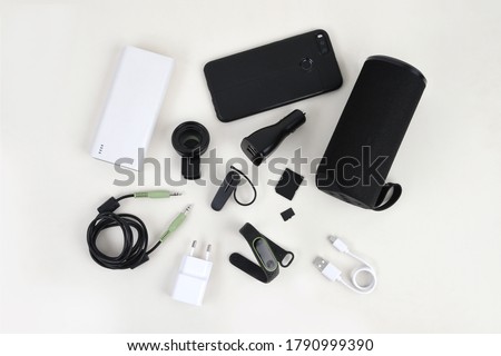 Arrangement mobile accessories layout includes power bank, speaker, charger, smart watch, headset, USB and AUX cable, microSD, adapter and macro clip lens flat lay