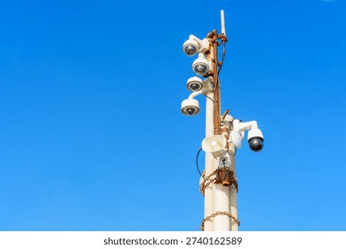 Array of advanced security cameras and a loudspeaker mounted on a pole, providing comprehensive surveillance coverage under a clear, cloudless blue sky.