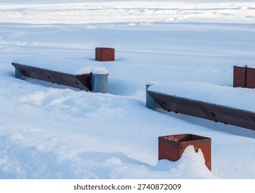 Array of the benches in a park covered with snow. Winter