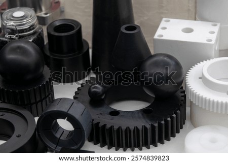 An array of black and white plastic spare parts arranged attractively in a modern display case highlights advancements in manufacturing techniques and material design.