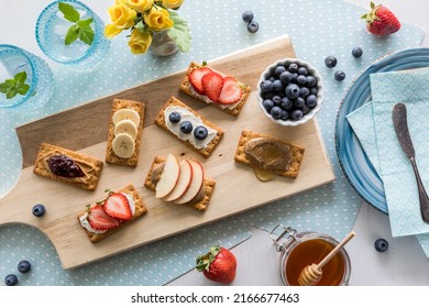 An array of breakfast crackers with a variety of toppings on a wooden board.