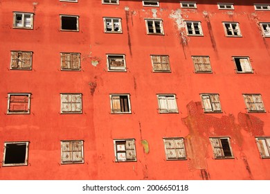 Array Of Broken And Nailed Shut Window Of An Orange-red Building Falling Into Decay