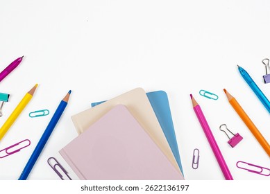 An array of colorful stationery including notebooks, pencils, and paper clips on a clean white backdrop.