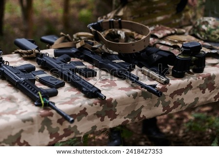 An array of military weapons, including rifles and pistols, is meticulously arranged on a table in a military base, presenting a close-up view of the diverse firepower and armament meticulously