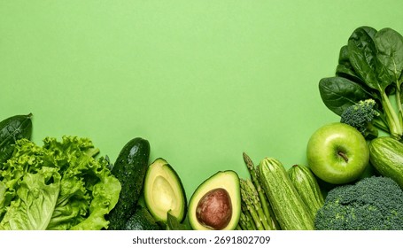 An array of various fresh green vegetables and fruits is neatly arranged on a bright green surface.