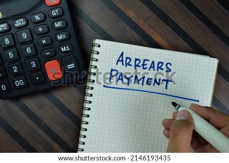 Arrears Payment write on a book isolated on Wooden Table.