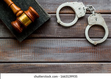 Arrest concept. Handcuffs near judge gavel on dark wooden background top-down copy space