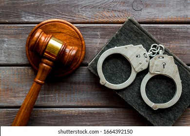 Arrest concept. Handcuffs near judge gavel on dark wooden background top-down
