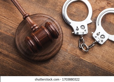 Arrest concept. Metal handcuffs near judge gavel
