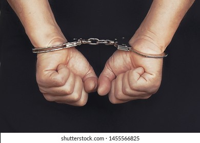 Arrested Elderly Man Handcuffed Hands At The Back Isolated On Black Background. Prisoner Or Arrested Terrorist, Close-up Of Hands In Handcuffs. Toning