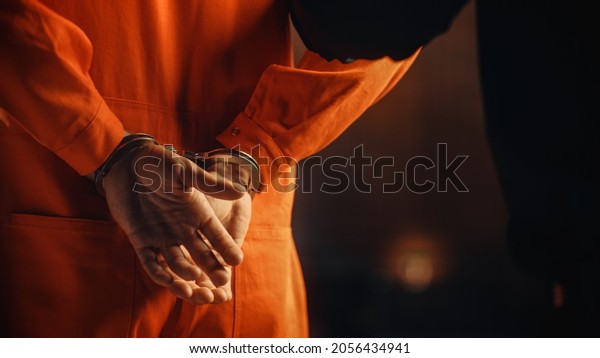 Arrested Handcuffed Convict at a Law and\
Justice Court Trial. Handcuffs on Accused Criminal in Orange Jail\
Jumpsuit. Law Offender Sentenced to Serve Jail\
Time.