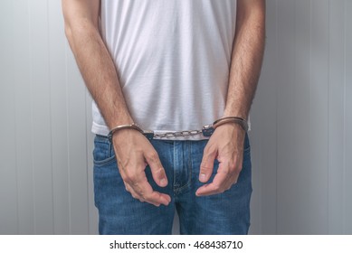 Arrested Man With Cuffed Hands. Unrecognizable Male Person In Jeans With Handcuffs Held In Police Station For Being Suspected Of A Crime.