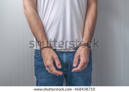Arrested man with cuffed hands. Unrecognizable male person in jeans with handcuffs held in police station for being suspected of a crime.