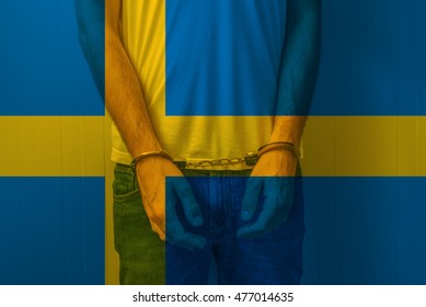 Arrested Man With Cuffed Hands Wearing Shirt With Swedish Flag. Unrecognizable Male Person In Jeans With Handcuffs Held In Police Station For Being Suspected Of A Crime.