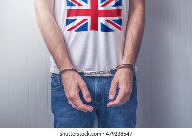 Arrested Man With Cuffed Hands Wearing Shirt With United Kingdom Flag. Unrecognizable Male Person In Jeans With Handcuffs Held In Police Station For Being Suspected Of A Crime.