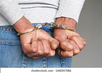 Arrested Man Handcuffed Hands At The Back. Prisoner Or Arrested Terrorist, Close-up Of Hands In Handcuffs.