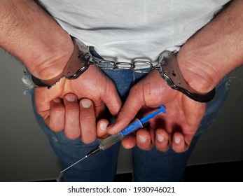 Arrested man holding injection syringe with drug, handcuffs on man,drug dealer loss freedom