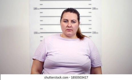 Arrested Overweight Woman In Front Of Police Lineup. Young Fat Lady Criminal Posing For Mugshot At Police Station