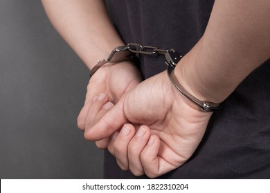 arrested person in handcuffs on a dark background close-up, chained hands on the back. - Shutterstock ID 1822310204