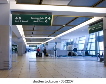 Arrival concourse at international airport with people walking toward luggage claim area; focus on foreground sign - Shutterstock ID 3362207