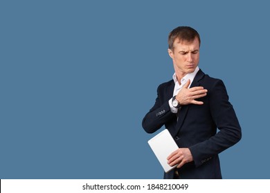 An Arrogant Male Businessman In A Suit Shakes The Dust Off His Clothes And Shoulder With Contempt. Studio Shot On A Blue Background With Space For Text.