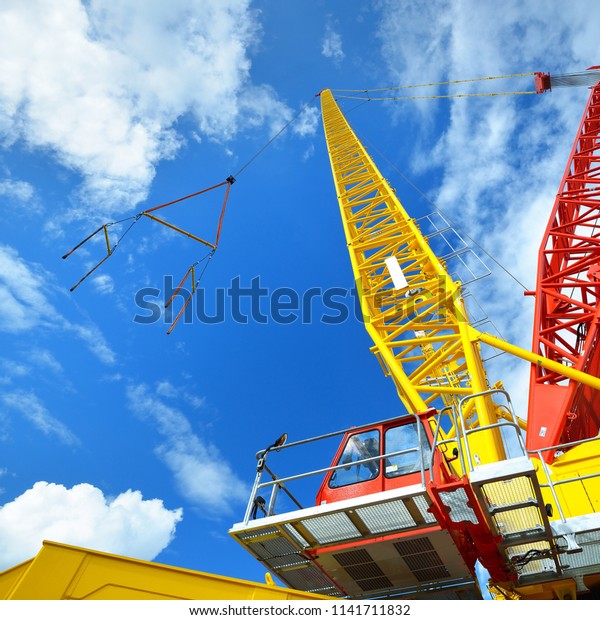 Arrow and\
cabin of a mobile crane against blue\
sky