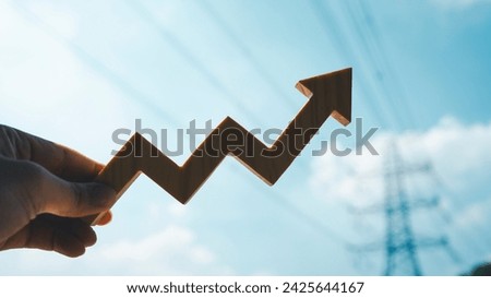 Up arrow graph with large electric pole in the background, concept of electricity bills, rising consumption costs and increasing electricity usage.