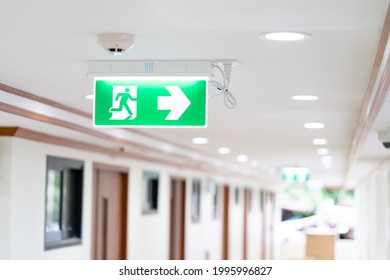 A Arrow light box sign of EMERGENCY FIRE EXIT is hung on the ceiling in hospital walkway, Idea for event fire or evacuation drills.