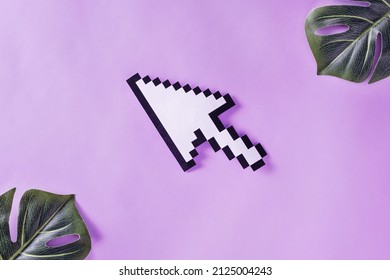 Arrow Pointer Is Pixelated On Pastel Purple Velvet Background And Leaves Of Monstera Plant. Surreal Retro Futuristic Concept.