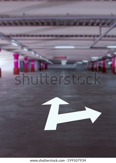 Arrow
pointers on the floor in the parking garage. Empty parking garage.
Arrow pointer travel forward. Blurred background. concept pointer
movement in the parking lot directly or
right.