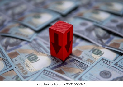 An arrow pointing downwards on top of a pile of US dollar bills. Economic recession, financial decline, economic downturn concept.