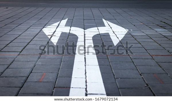 Arrow\
symbol on forked road. Make choice which way to go. Directional\
traffic arrow sign on street. Decision concept.\
