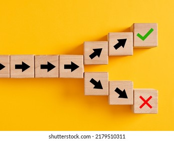 Arrow symbols on wooden cubes splitting into different directions towards right or wrong choices. Following the right or wrong path or choosing the right or wrong way.