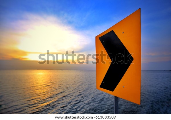 Arrow warning sign on footpath way, Perspective of\
arrow warning pathway sign and seascape background. Selective focus\
and toned image.
