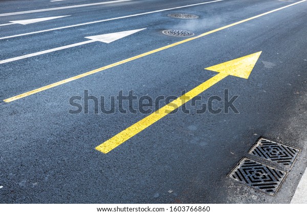 Arrows road\
marking on empty asphalt urban\
road